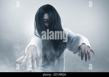 Gruselige Geisterfrau kriecht im Nebel. Halloween-Konzept Stockfoto