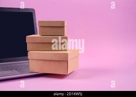 Vorderansicht auf Laptop-Computer und Verpackung Geschenk-Boxen auf pastellrosa Hintergrund mit Copyspace für Ihren Text. Saisonaler Verkauf, schwarzer freitag und Stockfoto