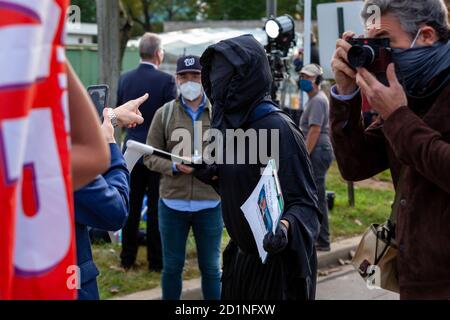 Bethesda, MD, USA, 5. Oktober 2020. Im Bild: Ein Mann, der als Sensenmann gekleidet ist, hebt seine Plastiksichel als letztes Mittel, um sich gegen einen verbalen und physisch aggressiven Trump-Unterstützer zu verteidigen. Ein Montgomery County Maryland Polizeibeamter musste eingreifen, um den Trump-Anhänger zu stoppen. Eine Reihe von Trump-Anhängern hatte sich vor dem Walter Reed National Military Medical Center versammelt, wo er nach der Ansteckung mit dem neuartigen Coronavirus für Covid-19 ins Krankenhaus eingeliefert wurde. Kredit: Allison C Bailey/Alamy Live Nachrichten Stockfoto