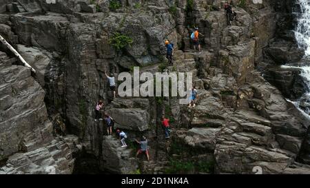 Kletterer auf der Klippe in der Nähe des Wasserfalls. Stockfoto