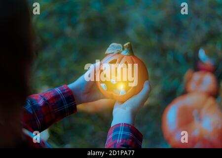 Kinder Hand hält Jack'O Kürbis Lampe, Trick or Treat an Halloween Tag. Konzept für Herbstferien Hintergrund. Stockfoto