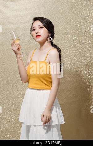 Feminine asiatische Modell heben Glas Champagner stehen über funkelt Hintergrund Stockfoto