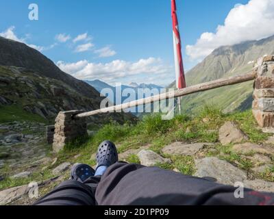 Wanderer Beine, Fuß in Gummikrümpfen Entspannung von der Nurnberger Hütte aus, Tal mit Berggipfeln am Stubaier Wanderweg, Sommer, Tirol, Stubai Stockfoto