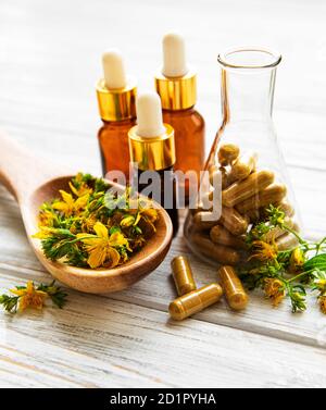 Johanniskraut, medizinische Kräuterpillen im Reagenzglas, Flaschen mit natürlichem Öl auf einem Tisch Stockfoto