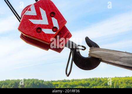 Roter Haken eines LKW-Krans, der in Transportposition hängt Auf dem Hintergrund der Natur Stockfoto