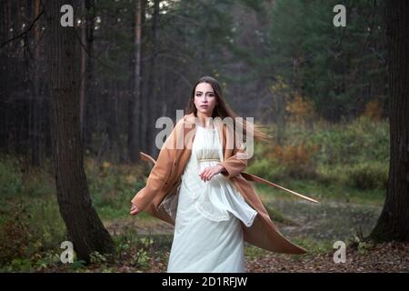 Mädchen in einem weißen Kleid und einem braunen Mantel in Der Herbstwald Stockfoto