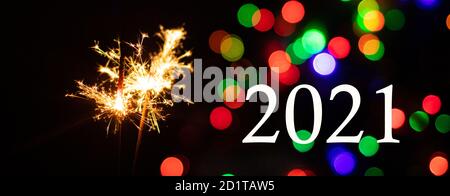 Bengalische Lichter mit goldenen Funkeln auf einem schwarzen festlichen Hintergrund mit mehrfarbigen Seiten. Neujahrsbanner mit den Zahlen 2021 und Sparkler. Stockfoto