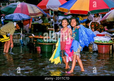 Junge Mädchen, die im Regen durch überflutete Straßen in Manila auf den Philippinen spazieren Stockfoto