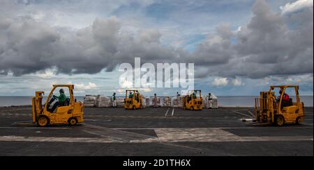 Seeleute nutzen Gabelstapler, um Vorräte zu einem Flugzeugaufzug auf dem Flugdeck des einzigen vorwärts eingesetzten Flugzeugträgers USS Ronald Reagan (CVN 76) während eines Nachschubes auf See mit Flottennachschuböler USNS Pecos (T-AO 197) zu transportieren. Ronald Reagan, das Flaggschiff der Carrier Strike Group 5, bietet eine kampfbereite Kraft, die die Vereinigten Staaten schützt und verteidigt, sowie die kollektiven maritimen Interessen ihrer Verbündeten und Partner in der Indo-Pazifik-Region. (USA Navy Foto von Mass Communication Specialist 2nd Class Samantha Jetzer) Stockfoto