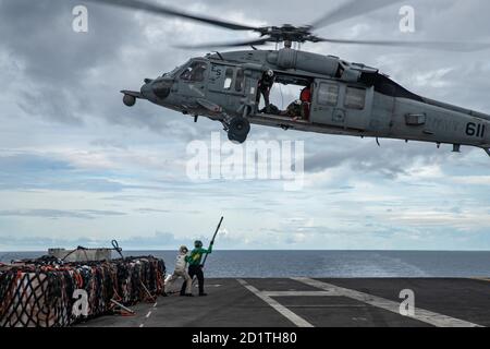 Logistik-Spezialist 3rd Class Justin Guy, rechts, aus Leonardtown, Maryland, und Kapitän Matthew Ventimiglia, Executive Officer der Navy einzigen vorwärts-Einsatz Flugzeugträger USS Ronald Reagan (CVN 76), befestigen Lieferungen an einem MH-60S Sea Hawk an der Golden Falcons of Helicopter Sea Combat Squadron (HSC) 12, Auf dem Flugdeck während einer Nachschubfahrt auf See mit Flottennachschuböler USNS Pecos (T-AO 197). Ronald Reagan, das Flaggschiff der Carrier Strike Group 5, bietet eine kampfbereite Kraft, die die Vereinigten Staaten schützt und verteidigt, sowie die kollektiven maritimen Interessen o Stockfoto