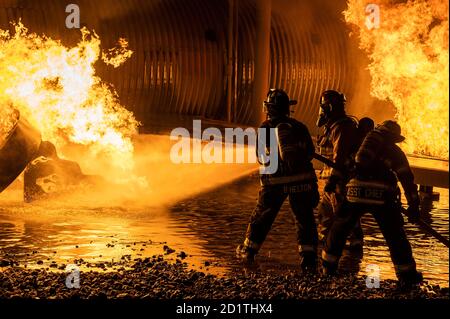 Feuerwehrleute aus dem 436. Bauingenieursgeschwader und Magnolia Volunteer Fire Company Station 55, aus Delaware, sprühen einen Flugzeug-Feuerwehrtrainer während einer Live-Feuerverbrennungsübung in der Nacht vom 28. September 2020 auf der Dover Air Force Base, Delaware. Die Schulungen werden verwendet, um die Kompetenz zu gewährleisten und andere jährliche Schulungsanforderungen für Feuerwehrleute zu erfüllen. (USA Luftwaffe Foto von Senior Airman Christopher Quail) Stockfoto