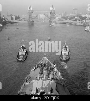 TOWER BRIDGE, Stepney, London. Blick hinunter auf das Vordereck des Kreuzfahrtschiffes HMS Belfast. Die Themse wird von zwei Schleppern auf dem Weg zur Tower Bridge hinauf geführt, die sich öffnet, um sie passieren zu lassen. Dies war Belfasts letzte Reise, bevor sie im Pool von London festmachte. Es wurde dort zu einer statischen Besucherattraktion umgebaut und wird jetzt vom Imperial war Museum betrieben. Fotografiert von Eric de Mare im Jahr 1971. Stockfoto