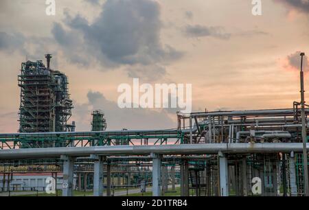 Raffinerieturm an einer petrochemischen Anlage mit bewölktem Himmel. Nach Sonnenuntergang. Stockfoto