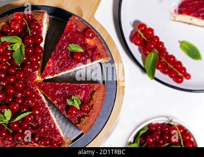 Käsekuchen mit roter Johannisbeere und Minze auf Holzbrett. Draufsicht. Stockfoto