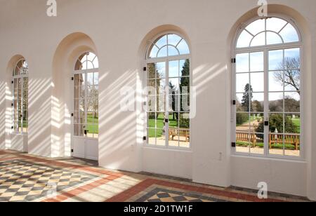 WREST PARK HAUS UND GÄRTEN, BEDFORDSHIRE. Innenansicht der Orangerie mit Blick auf den Garten, mit gedapptem Sonnenlicht, das durch das Glasdach filtert. Stockfoto