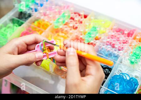 Gummiband Webt. Strickgummibänder mit Webstuhl-Strick. Hände des Mädchens Weben Armband aus Gummibändern. Stockfoto