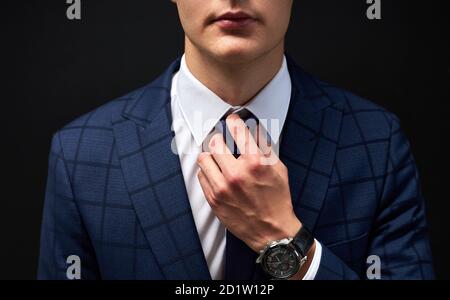 Cropped Business Mann gerade eine Krawatte isoliert über schwarzem Hintergrund. Junge Kerl in formellen Anzug Vorbereitung für die Sitzung Stockfoto