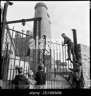 Eine Gruppe von Kindern klettert die schmiedeeisernen Tore am Kanal Seiteneingang zu George Goodwin und Sons' Westwood Mills, Lichfield Street, Hanley, Stoke-on-Trent, Staffordshire, Großbritannien. Stockfoto