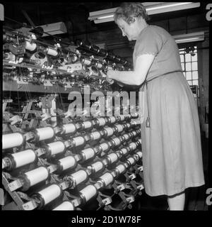 Eine Frau, die eine Garnverdoppelungsmaschine in den Räumlichkeiten von Bentley und Whittles, Seidenherstellern, in Wellington Mills, Strangman Street, Leek, Staffordshire Moorlands, Staffordshire, Großbritannien, betreibt. Stockfoto