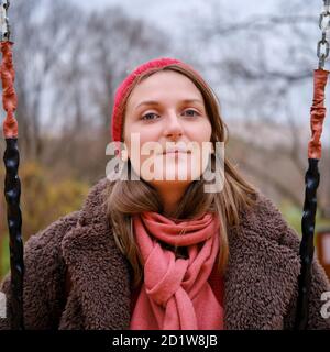 Lächelnde Frau im Herbstpark sitzt auf einer Schaukel, Nahaufnahme Porträt Stockfoto