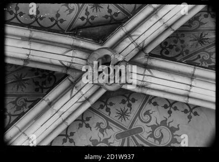 Detail eines Bosses, der in ein Paar Meerjungfrauen auf der gewölbten Decke geschnitzt wurde, wahrscheinlich im Kirchenschiff, aufgrund der gemalten Dekoration zwischen den Rippen des Gewölbes. Stockfoto