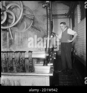 Ein Mann bei der Arbeit in der Färöer von Wellington Silk Mills. Stockfoto