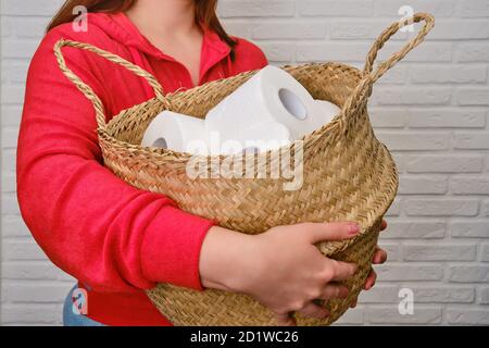 Korbkorb mit Toilettenpapierrollen in Frauenhänden, Nahaufnahme. Panik beim Kauf von Toilettenpapier in der Krise wegen des Coronavirus epidemii Stockfoto