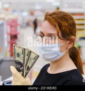 Ein Kunde in einer medizinischen Maske steht mit Geld in den Händen im Laden, ein Nahaufnahme-Portrait Stockfoto