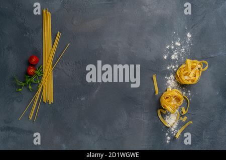 Pasta italienische Küche. Pasta Tagliatelle und Zutaten zum Kochen auf dunklem Hintergrund, Draufsicht. Stockfoto