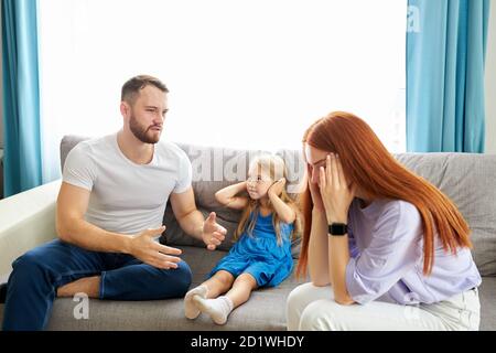 kaukasische Kind Mädchen leidet unter Streitigkeiten zwischen Eltern in der Familie zu Hause, Rothaarige Frau und bärtigen Kerl argumentieren in Anwesenheit von Tochter Stockfoto