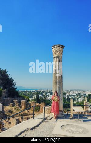 Mädchen in der Nähe der Ruinen von Karthago. Säule auf dem Hügel Byrsa an der römischen Marmorsäule, in der Nähe des punischen Hafens. Stockfoto