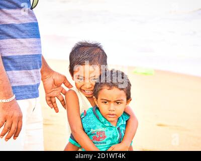 PUDUCHERRY, INDIEN - DEZEMBER CIRCA, 2018. Unidentifizierte schüchterne peinliche Söhne, die in der Nähe seines Vaters in der Straße eines Dalit-Dorfes stehen Stockfoto