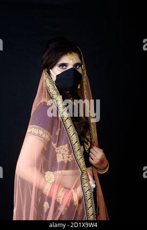 Braut trägt weiße indische traditionelle Tuch mit Gesichtsmaske während Hochzeitsfeier in Indien Stockfoto