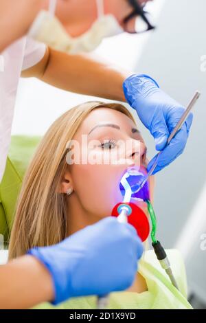 Junge Frau beim Zahnarzt. Zahnarzt besteht in der Reparatur der Zähne. Stockfoto