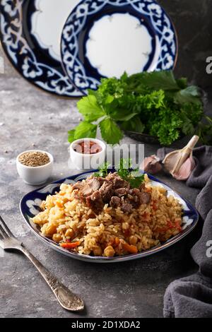 Traditionelle azianische Pilaf in Ornamentplatte auf grauem Hintergrund Stockfoto