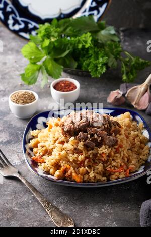 Traditionelle azianische Pilaf in Ornamentplatte auf grauem Hintergrund Stockfoto