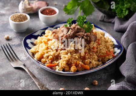 Traditionelle azianische Pilaf in Ornamentplatte auf grauem Hintergrund Stockfoto