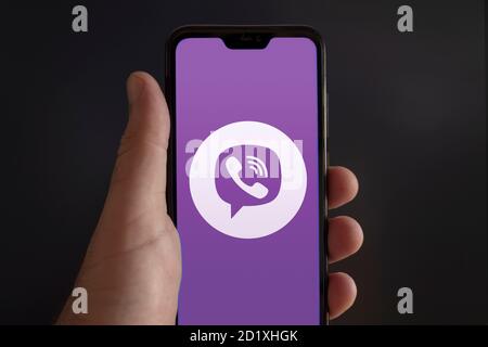 Der Bildschirm eines Smartphones von einer männlichen Hand gehalten Mit Viber Messenger Video Konferenz App Logo auf einem schwarzen Hintergrund Stockfoto