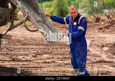 Bauarbeiter, die Zement oder Beton in die Fundamentschalung legen. Gebäude Haus Fundament Stockfoto