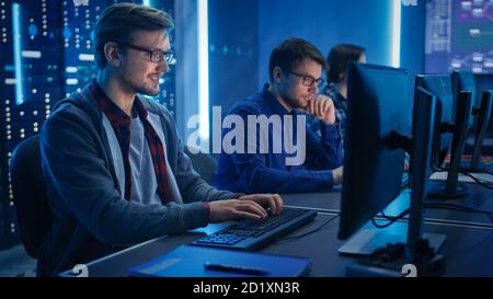 Team von jungen IT-Programmierern, die an Desktop-Computern im Kontrollraum des Rechenzentrums arbeiten. Zeigt Konzept Anzeigen: Software-Entwicklung Code Schreiben Stockfoto