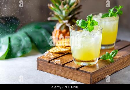 Frisch gepresster Ananassaft mit Ananasscheiben auf hellgrauem Betongrund. Konzept des sommerlichen gesunden Fruchtgetränks. Stockfoto