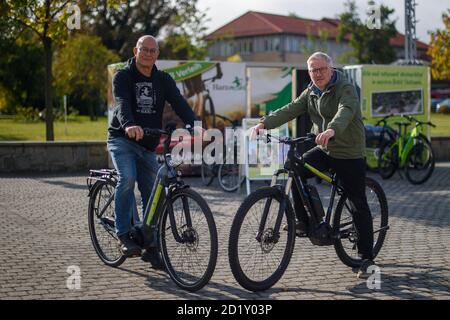 Wernigerode, Deutschland. Oktober 2020. Alexander Waturandang (l.) und Mario Wermuth vom Fahrradladen 'Harzmobil' sitzen vor ihrer Verleihbox auf E-Bikes, die sie dort mieten. Die temporäre Box steht seit Anfang September auf dem Platz in der Nähe des Bahnhofs. Bis Ende Oktober können Touristen, die am Bahnhof ankommen, elektrische Stadtfahrräder, E-Mountainbikes oder elektronische Motorroller mieten. Quelle: Klaus-Dietmar Gabbert/dpa-Zentralbild/ZB/dpa/Alamy Live News Stockfoto