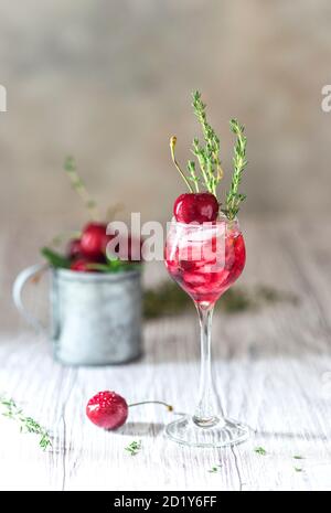 Kirschcocktail. Frischer Sommercocktail mit Kirsche, Thymian und Eiswürfeln. Stockfoto