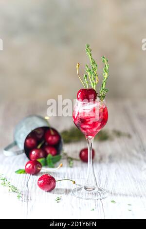 Kirschcocktail. Frischer Sommercocktail mit Kirsche, Thymian und Eiswürfeln. Stockfoto