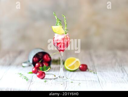 Kirschroter Cocktail mit Limette. Frischer Sommercocktail mit Kirschen, Thymian und Eiswürfeln. Stockfoto