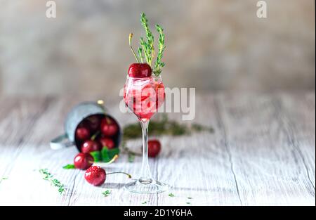Kirschcocktail. Frischer Sommercocktail mit Kirsche, Thymian und Eiswürfeln. Stockfoto