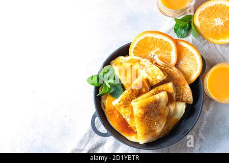 Crepes mit Orangensauce in einer gusseisernen Pfanne. Traditionelle französische Crepe Suzette mit Orangensauce. Stockfoto