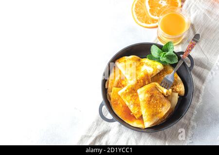 Crepes mit Orangensauce in einer gusseisernen Pfanne. Traditionelle französische Crepe Suzette mit Orangensauce. Stockfoto