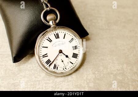 Alte Taschenuhr gegen schwarzes Kissen und grauen texturierten Hintergrund. Römische nummern, die die Zeit angeben Stockfoto