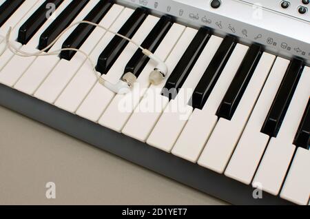 Tastatur des Synthesizers oder elektronisches Musikinstrument mit Ohrstöpseln Oder Ohrhörer Stockfoto